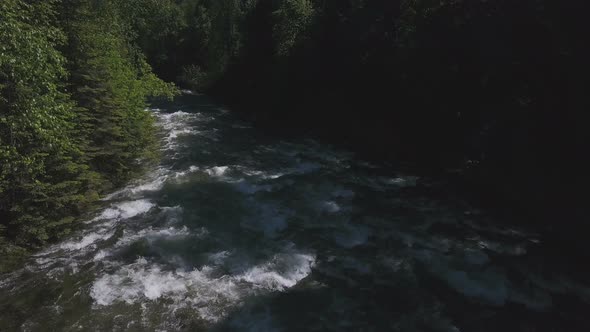 Aerial Drone Traveling Along Water Rapids Between Evergreen Forest 1