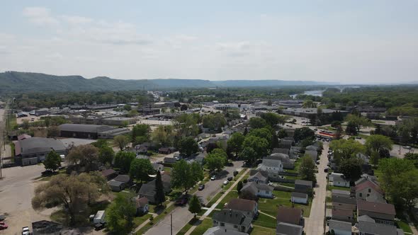 Aerial view of city in valley with mountains and river, tree lined streets with blue sky.