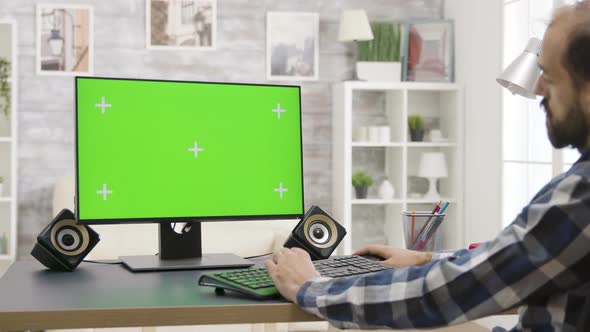 Man Works on Isolated Green Screen PC Display in Bright, Well Lit Living Room alt