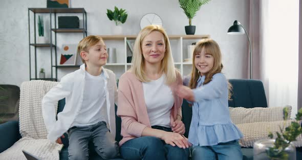 Woman Sitting front of Camera and Hugging with Her Daughter and son alt