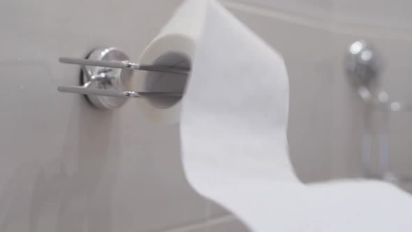 Slow Motion: Toilet Paper Is Unwound Which Is Hanging on the Wall in the Bathroom alt