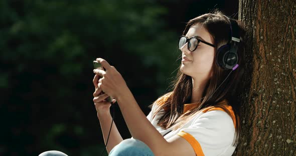 Woman in Headphones Listening To Music in Park