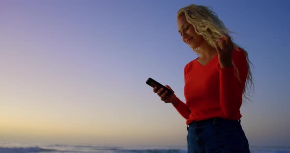 Woman using mobile phone on beach at dusk 4k
