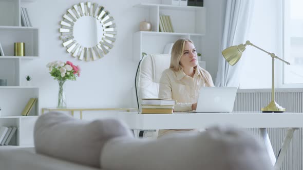 Thinking young girl while sitting at work in a laptop in a white room at home alt