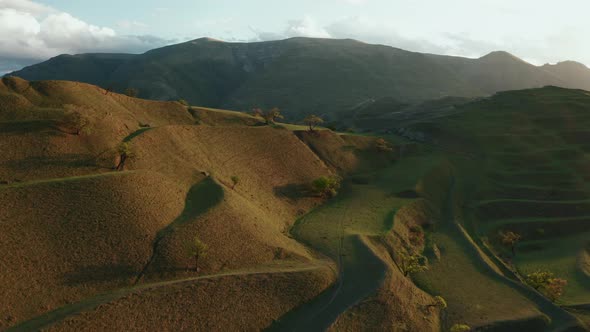 Aerial view of mountain hills, terraces on sunset, countryside landscape with tractor