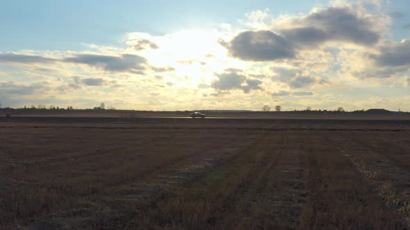Aerial View Car Rides on The Road in The Field at Sunset alt