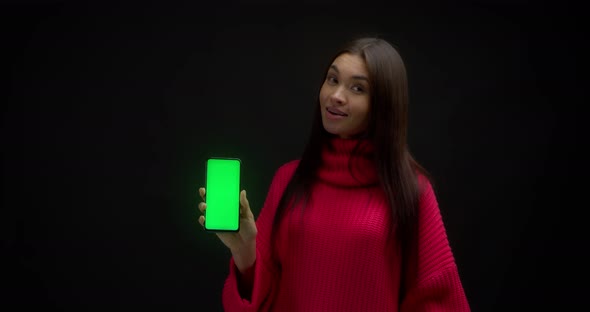 Woman in a Pink Sweater Shows Vertical Green Phone Screen for Copying