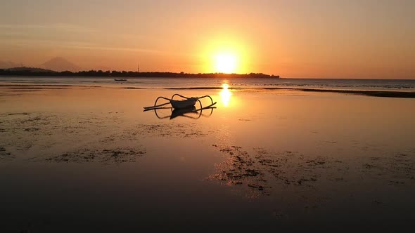 Aerial video of a boat silhouetted in the sunset on a beach in Bali, Indonesia (2) alt