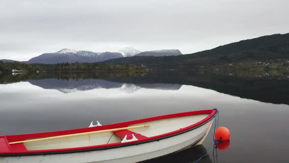 Wooden Boat Reflected Floating In A Norwegian Fjord - aerial drone shot alt