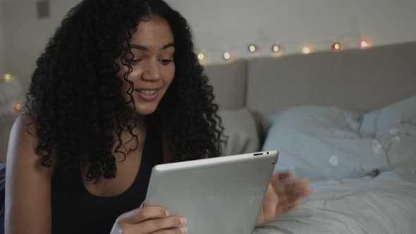 Young woman in Bedroom looking using digital tablet