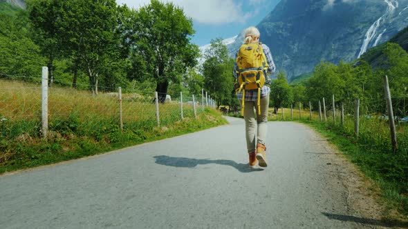 The Incredibly Beautiful Nature of Norway - a Woman with a Backpack Walking Along a Path alt