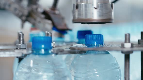 Water Factory Industrial Machine Puts Caps on Plastic PET Bottles with Water Close Up