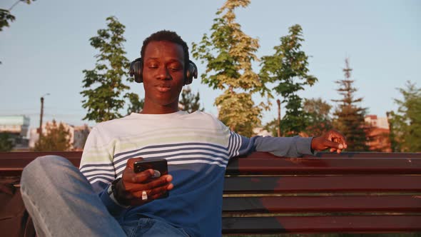 Black Young Man Listens to Music with Headphones