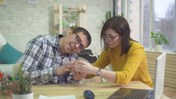 Adult Male Autistic and Assistant Learning How To Handle a Smartphone alt