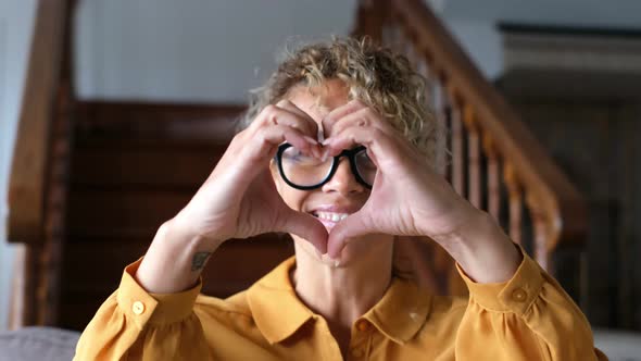 Portrait of beautiful adult woman at home doing hearth sign with hands - concept of happy lifestyle alt