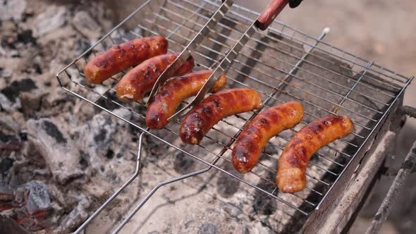 Closeup View of Tasty Sausages Grilling on Charcoal Grill Grate alt
