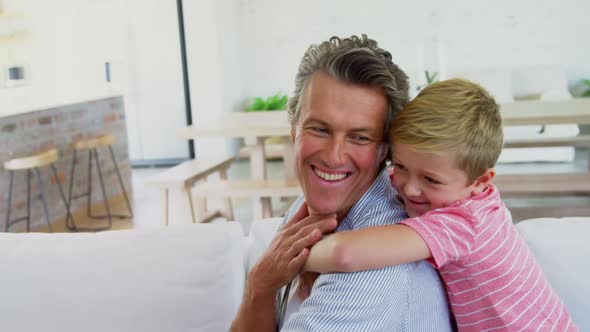 Happy father and son relaxing on sofa in living room 4k alt