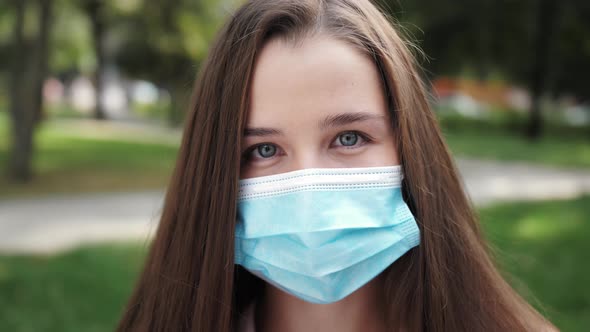 Portrait of a woman about in the city streets during the day, wearing a protective virus face mask. alt