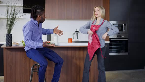 Wide Shot of Angry Caucasian Woman Arguing with African American Man in Kitchen at Home alt