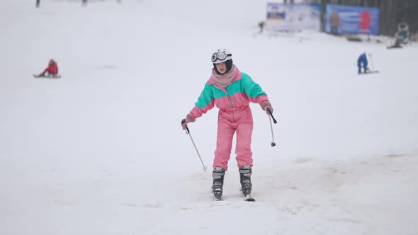 Wide Shot of Female Tourist Skiing on Snowy Slopes Outdoors alt