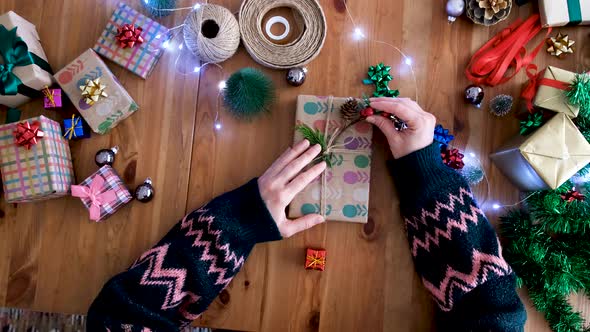 Carefully places the conifer pine branch on the gift package