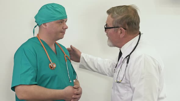 Mature Doctor Discusses with a Young Colleague in the Hospital Corridor alt