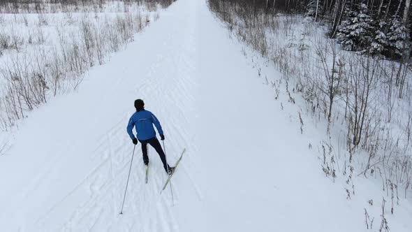 Professional Athlete Skies Along Snowy Track Among Forest alt