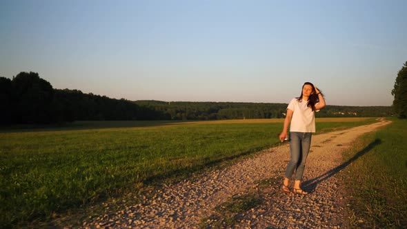 Female Walks Along Road in Field Turns to Sun Turns Back Continues to Walk