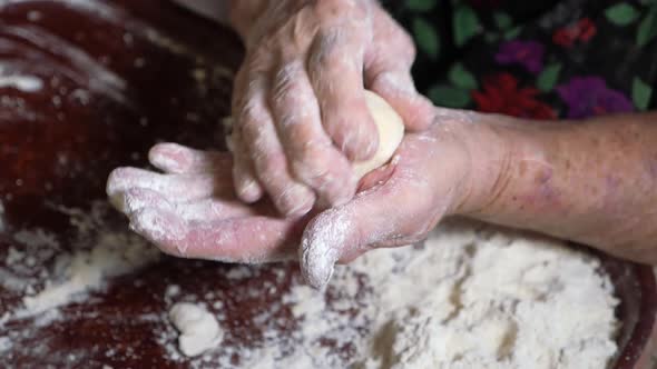 Wrinkled Hands of an Elderly Man Knead the Dough and Make Balls of Kolobok alt
