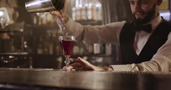 Close-up Shooting. Bartender Is Pouring the Alcohol From the Shaker Through a Cocktail Strainer Into alt