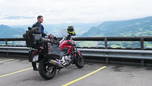 Biker on Tourist Motorbike with Luggage Bags Stands By Mountain Landscape Alps alt