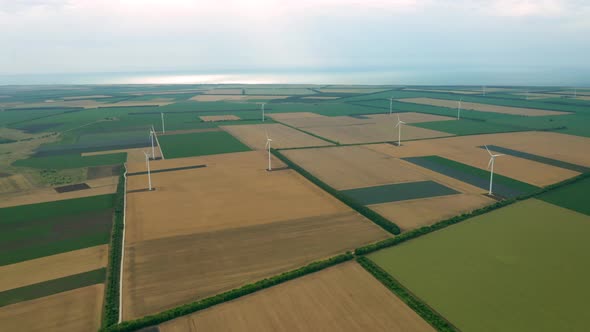 Wind turbines across summer agricultural field alt