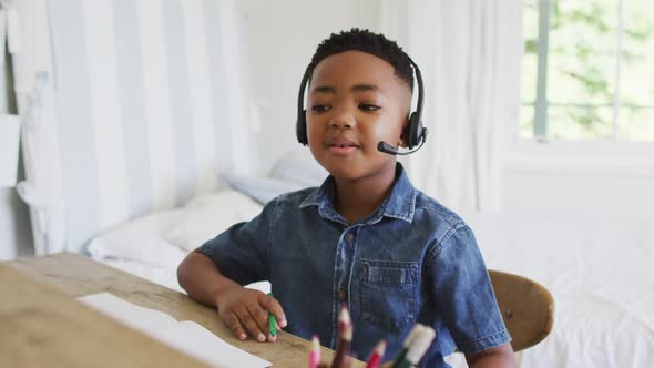 Portrait of african american at home in online school class, using headset looking at camera alt