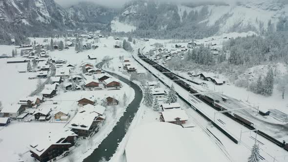 Aerial of cargo train parked in snow covered small town alt
