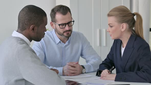 Businesswoman Explaining Documents to Male Colleagues alt