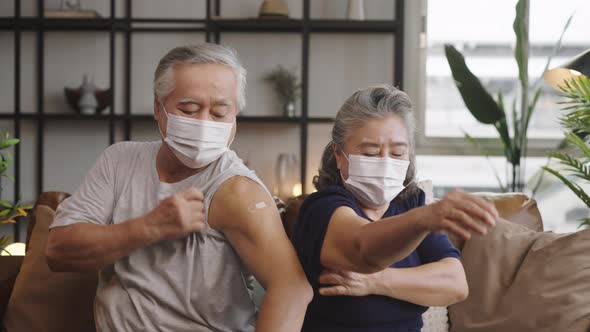 Asian mature couple show shoulder with band aid after injection vaccinated. alt