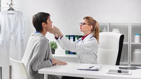 Professional Doctor Examining Neck Thyroid and Eyes of Woman Patient During Regular Medical Checkup alt
