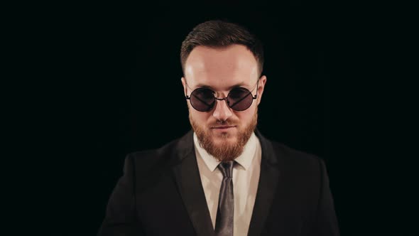 A Man in a Suit is Standing on Stage and Looking at the Camera alt