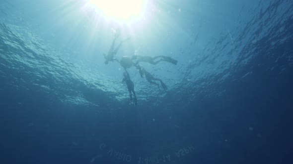 Underwater Shot of Freedivers Holding a Buoy in the Blue Sea with Sunrays. alt