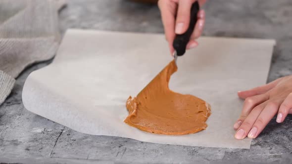 Spreading the Raw Caramel Dough Over a Parchment Paper Sheet