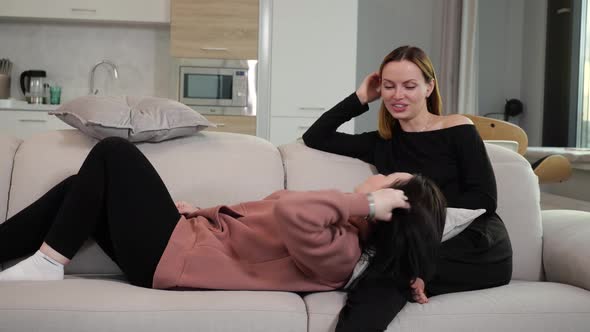 the Girl Put Her Head on Her Friend's Lap While Lying at Home on the Sofa