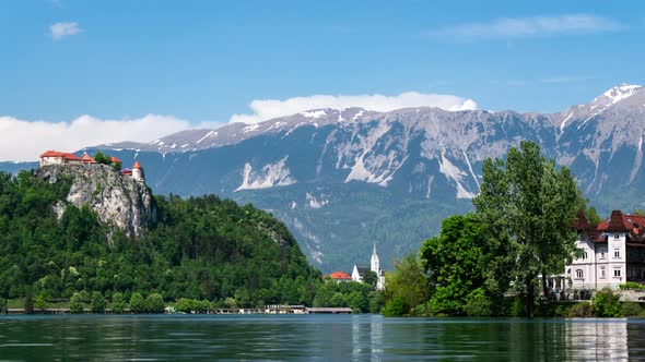 time lapse of lake Bled Slovenia castle on top of a cliff with mountains in background and clouds fo alt