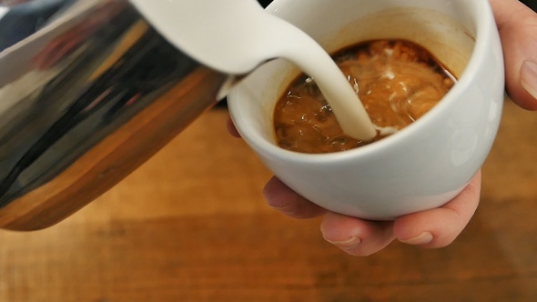 Pouring Stream Milk Into a Cup of Espresso