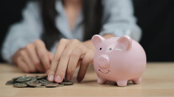 Saving money concept, Woman hand putting money coin into piggy bank. Close up.
