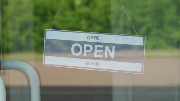 A Man Changes a Sign That Says OPEN for a Sign That Says CLOSED During the COVID19 Pandemic alt