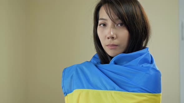 Portrait of an Asian Woman with a Ukrainian Flag on Her Shoulders