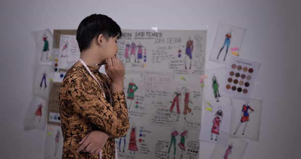 Asian clothing designer working in his office, creating a new clothes collection alt
