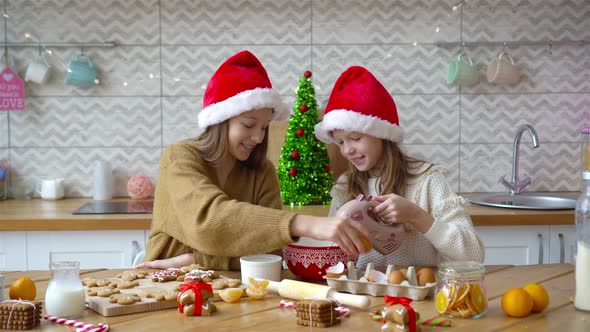 Little Girls Making Christmas Gingerbread House at Fireplace in Decorated Living Room