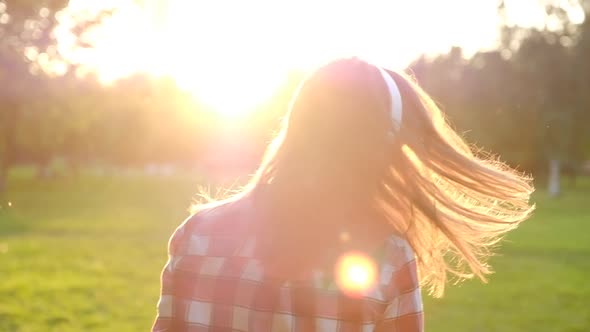 Rear view of a beautiful young woman in casual wear enjoying music