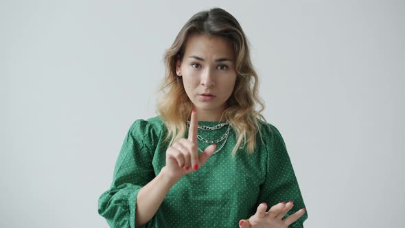 Slow Motion of Serious Young Woman Touching Lips with Finger and Making Calm Down Hand Gesture alt